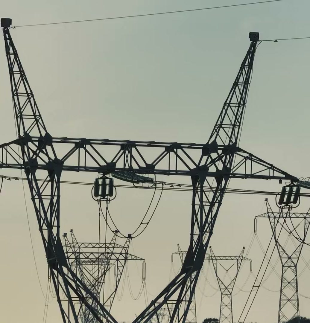 High-voltage pylons and their lines against a hazy evening sky